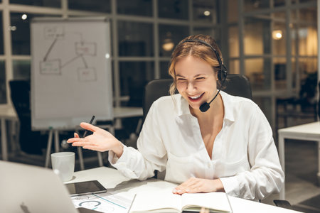 Female professional working on laptop with headset in modern office