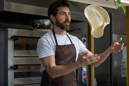 Man tossing dough in mid-air while concentrating on its movementの写真素材