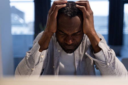 African american man at the laptop looking tired and suffering from a headacheの写真素材