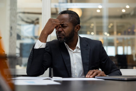 African american businessman having a headache after a busy working dayの写真素材