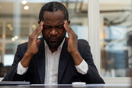 African american businessman having a headache after a busy working dayの写真素材