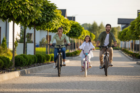 Family bike outing on residential path with trees and homes