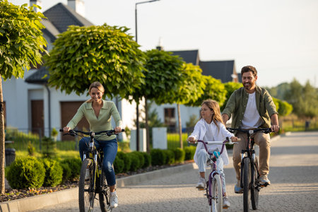 Family bike ride along tree-lined path near modern housesの写真素材