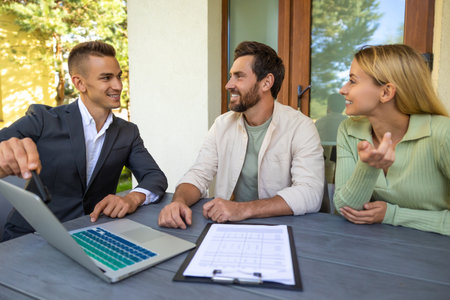 Agent presenting house details to clients with laptop in