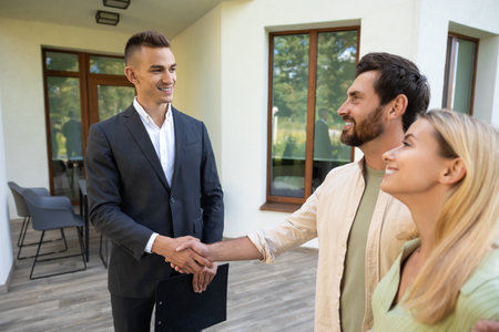 Pair celebrating home purchase with agent in green yard areaの写真素材