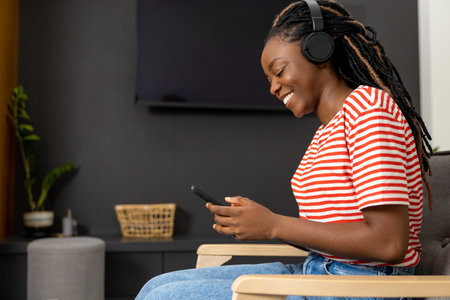 Cute african american young woman in headphones looking happy and enjoyed