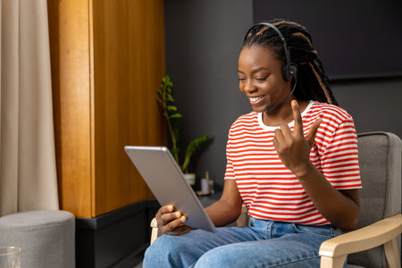 Cute african american young woman in headphones with a tablet in hands