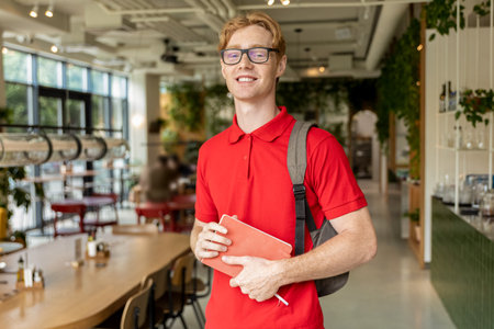 Young ginger man in eyeglasses looking confident and smiling nicely