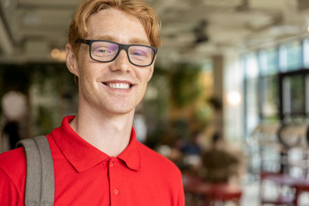 Young ginger man in eyeglasses looking confident and smiling nicelyの写真素材