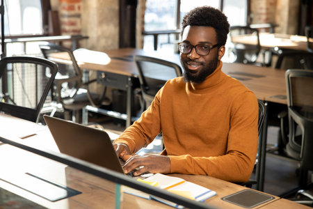 African american young man with laptop working in the officeの写真素材