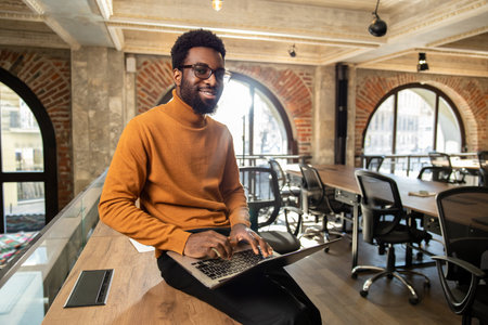 African american young man with laptop working in the office