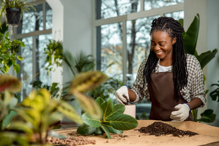 Contented and enjoyed young woman planting flowers and looking busyの写真素材