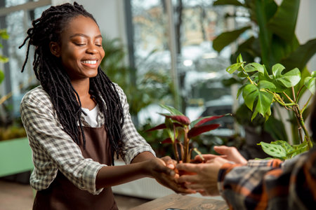 Flower shop assistant selling flower to the customer and smiling nicelyの写真素材