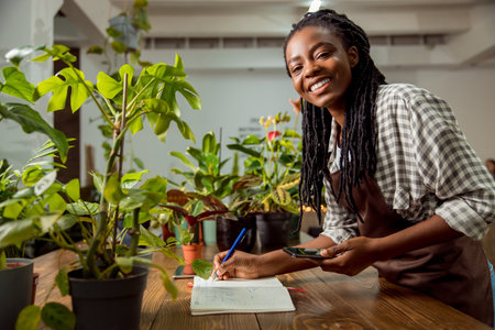 Flower shop assistant making notes and smiling nicelyの写真素材
