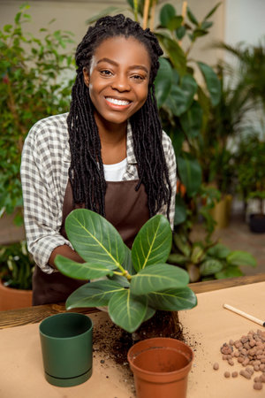 Cute african american florist planting flowers in the flower shopの写真素材