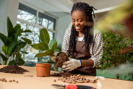 Smiling flower shop assistant planting flowers and feeling good