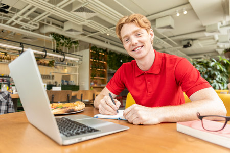Young man studying in a cafe and looking positiveの写真素材