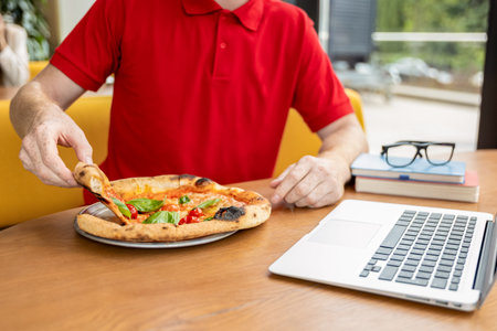 Young man in pizzeria looking positive and preparing to eat pizzaの写真素材