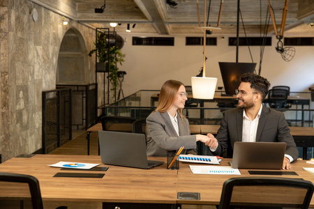 Business partners shaking hands and looking excited before conversation