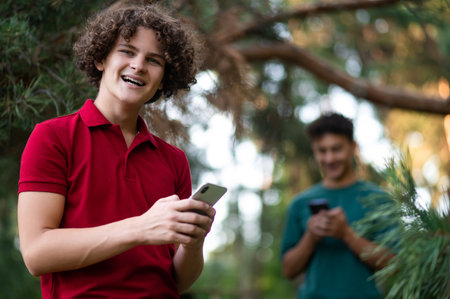 Two teens with phone in hands in the park