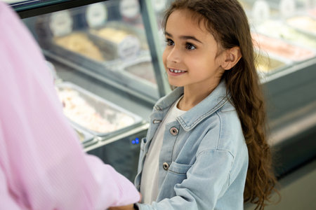 Woman and little girl with long curly hair choosing frozen dessertsの写真素材