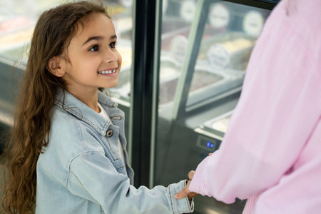 Smiling mother and daughter choosing ice cream in modern dessert shopの写真素材