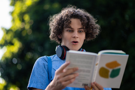 Teen reading a book and looking surprised and impressed