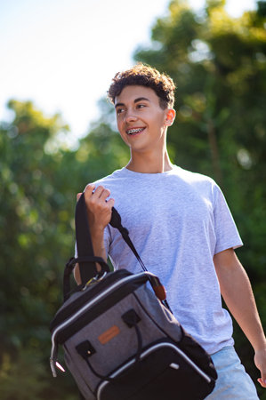 Contented teen with a backpack walking in the park