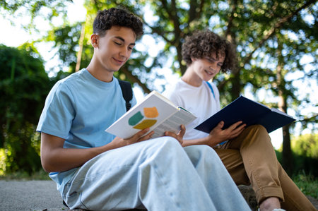 Two teens in the park preparing for the lessons and reading a bookの写真素材