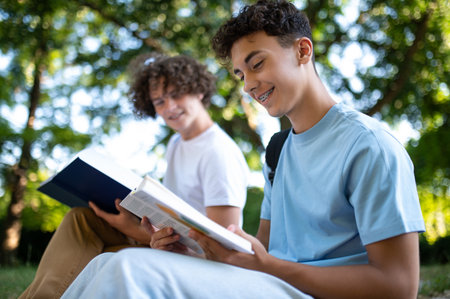 Two teens in the park preparing for the lessons and reading a bookの写真素材