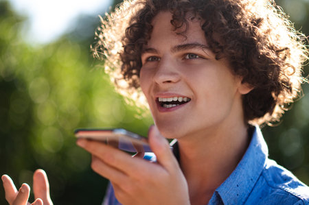 Curly-haired teen with a phone in hands in the park