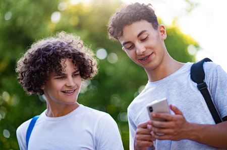 Two teens spending time together and watching something on the phoneの写真素材