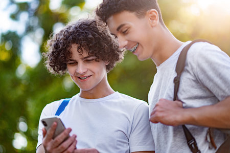 Two teens spending time together and watching something on the phoneの写真素材