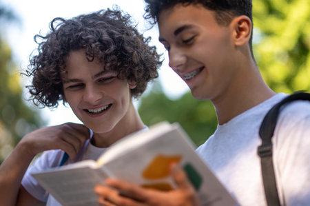 Two teens reading books together and looking enjoyed