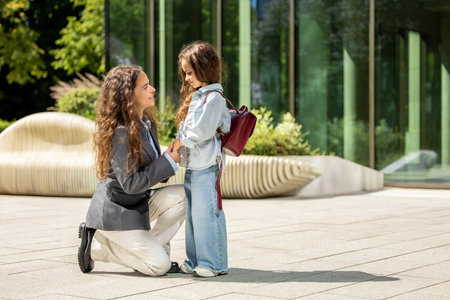 Confident mother with her daughter wearing backpack and folderの写真素材