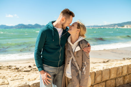 Couple embracing intimately on sunny beach with ocean viewの写真素材