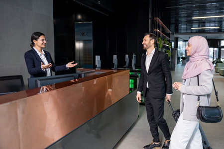 Nice couple standing near reception and talking to the receptionistの写真素材