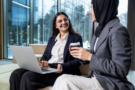 Two women sitting together, talking and looking involved and excited