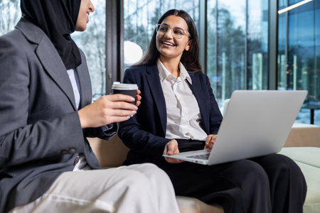 Two women sitting together, talking and looking involved and excited