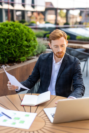 Corporate worker handling paperwork and laptop using in open-airの写真素材