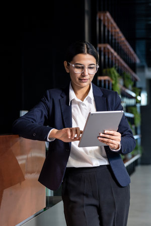 Stylish caucasian dark-haired woman with tablet in hands in the office