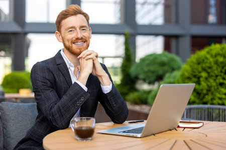 Red-haired man professional posing at outdoor workspace with computerの写真素材