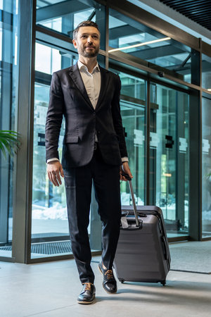 Man in formal wear carrying a suitcase while entering the business centerの写真素材