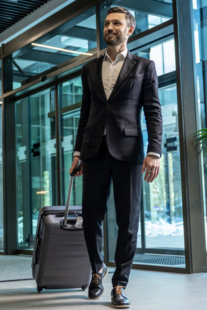 Man in formal wear carrying a suitcase while entering the business centerの写真素材