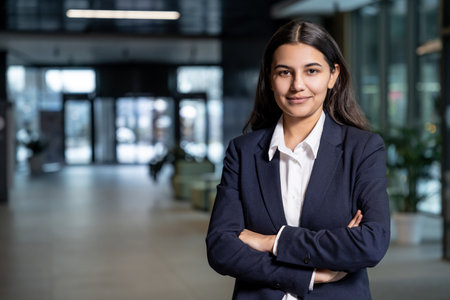 Cute young woman in jacket and white shirt standing with her arms crossedの写真素材