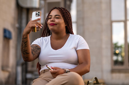 Female osing outdoors using phone camera for applying lipstick