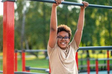 Curly-haired boy in eyeglasses spending time at the playground
