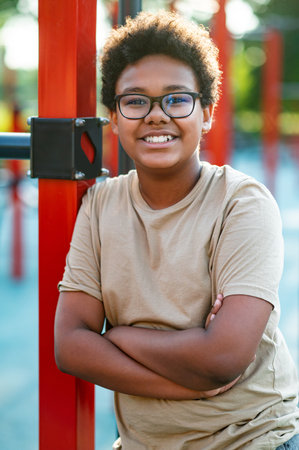 Smiling teen in eyeglasses standing with his arms crossed and looking confidentの写真素材