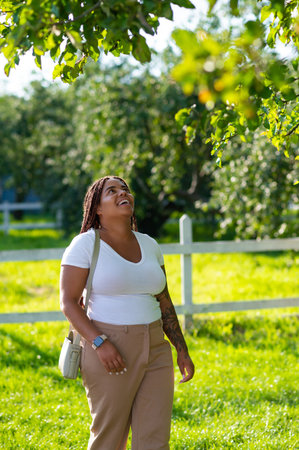Smiling plus size woman standing park in stylish outfitの写真素材