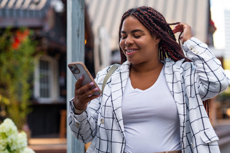 Female using smartphone standing in city backgroundの写真素材